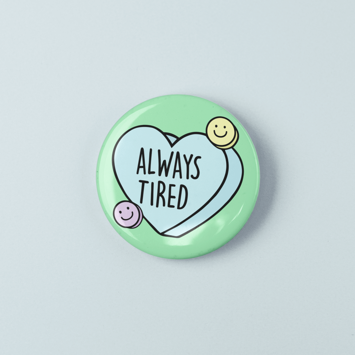 Button badge with 'Always Tired' text on a light blue background