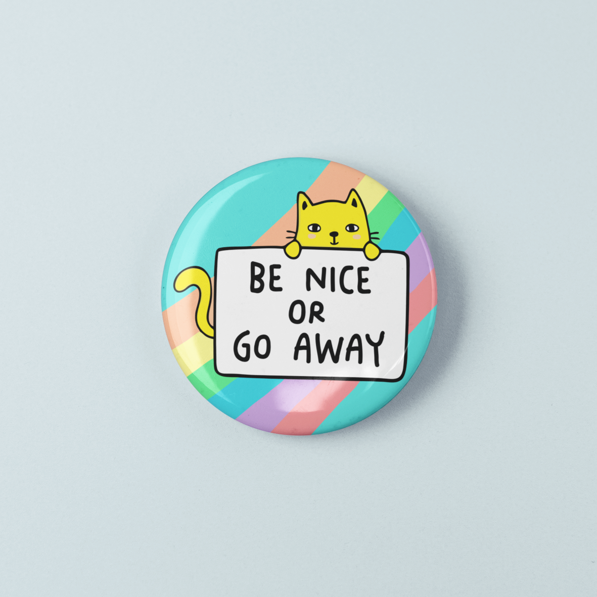 Button badge with a cat illustration and text 'Be nice or go away' on a pastel rainbow background.