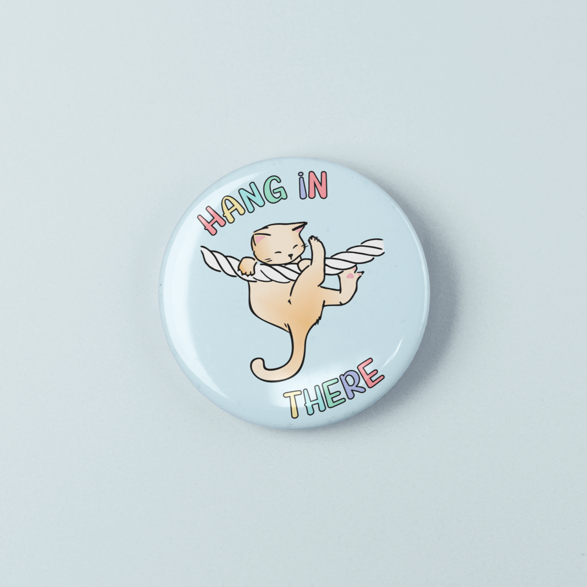 Button badge with a cat illustration and text 'Hang in there' on a light blue background