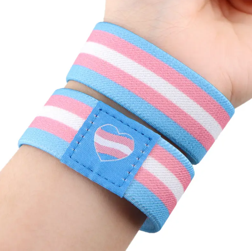 Two striped wristbands with a heart design on a wrist against a white background