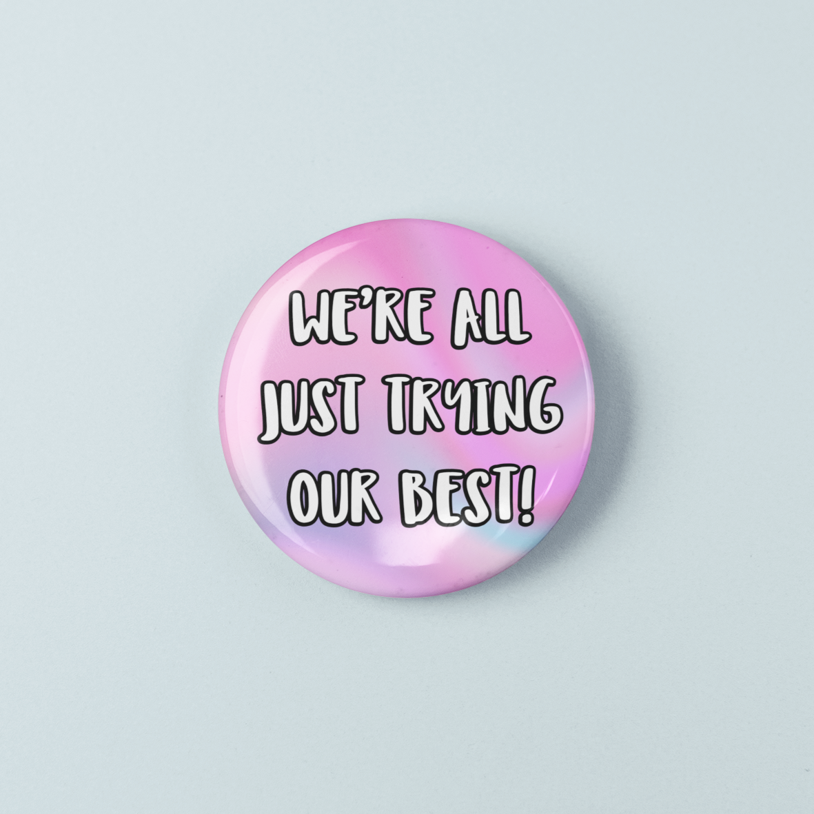 Button badge with 'We're all just trying our best!' text on a pastel gradient background