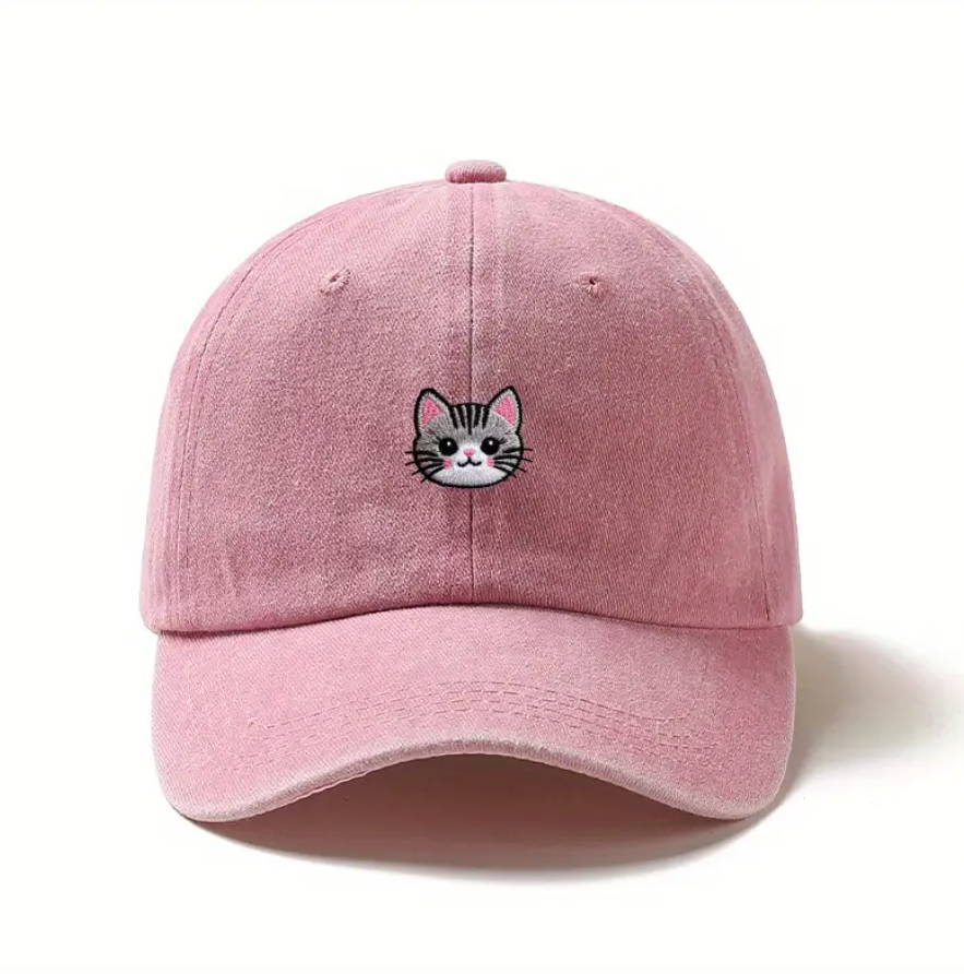 Pink baseball cap with a cat face design on a white background