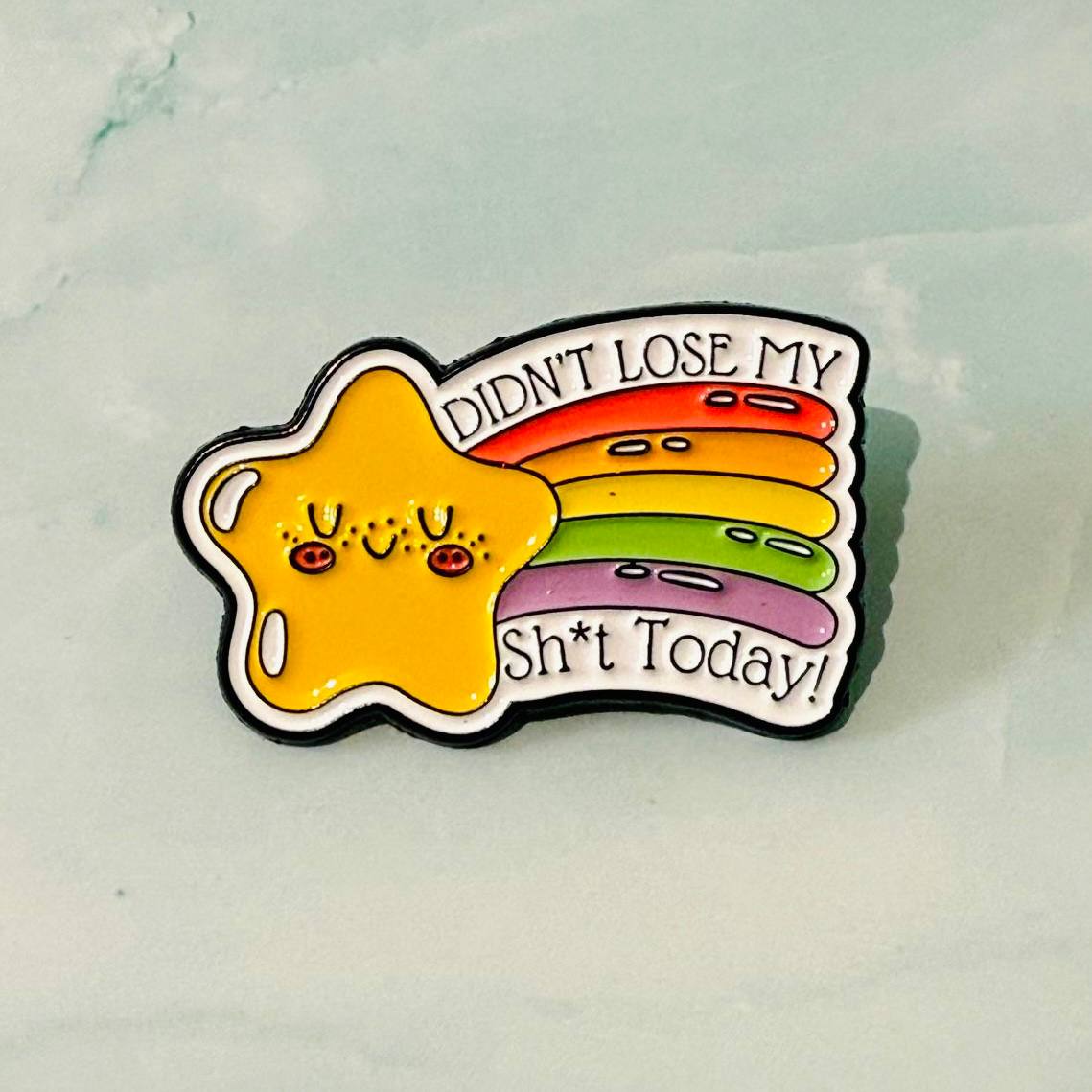 Colorful enamel pin with a star and text on a light background