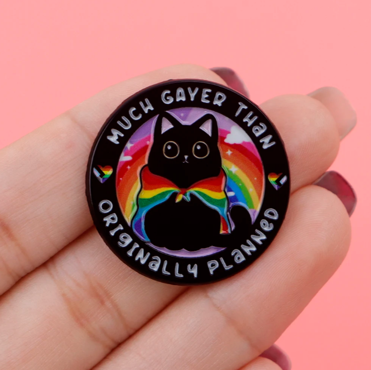 Button badge with a black cat in a rainbow bow tie and text on a pink background