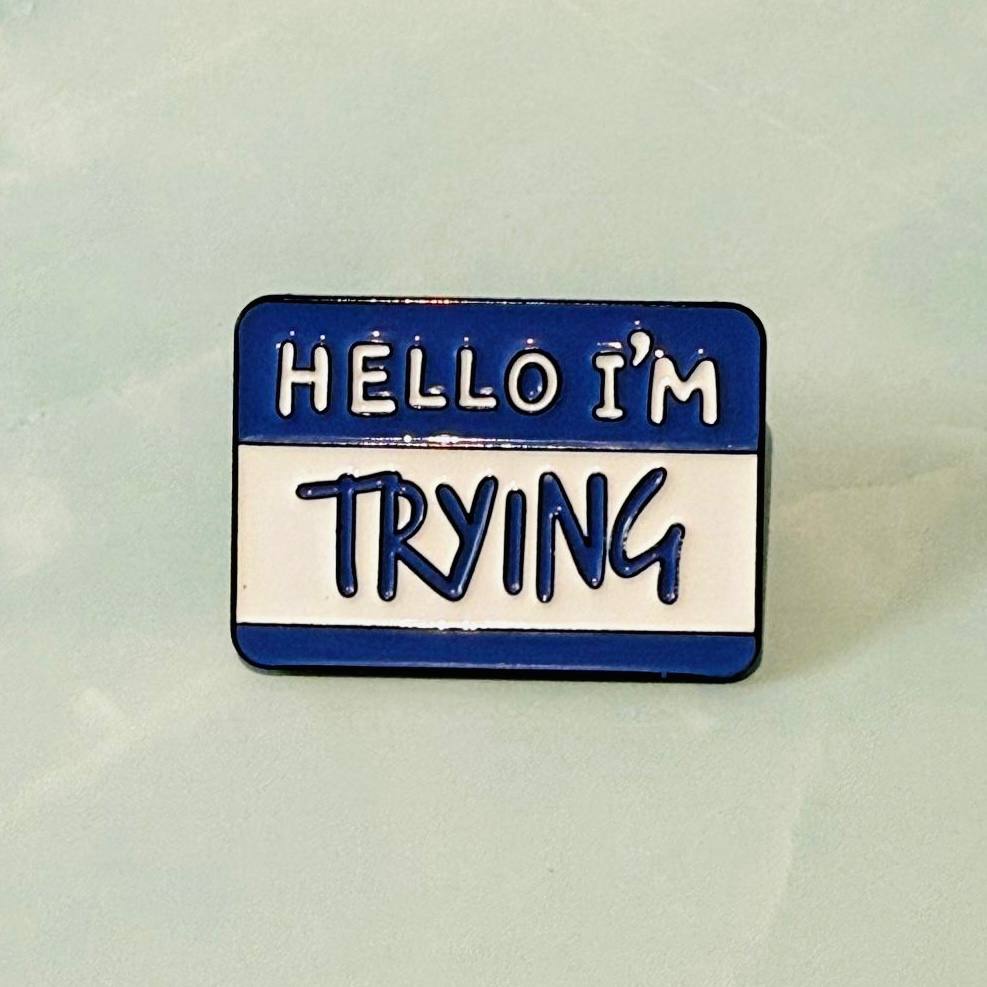 Pin with 'HELLO I'M TRYING' text on a light green background