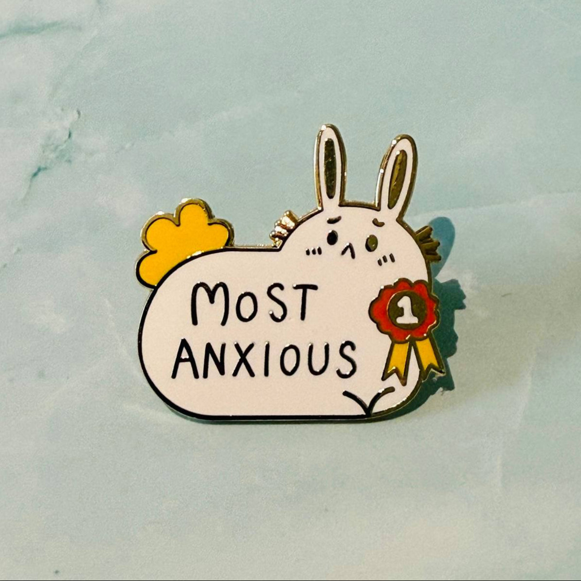 Pin with cartoon rabbit holding a sign saying 'Most Anxious' on a light blue background