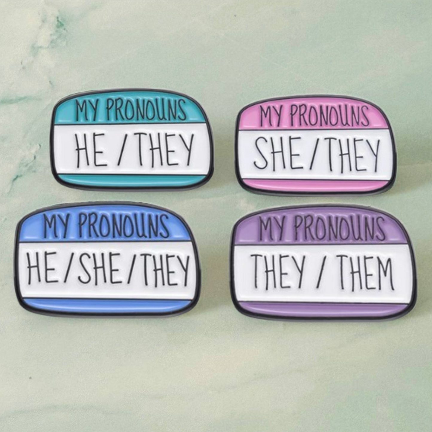 Fourpronoun pins on a light green background