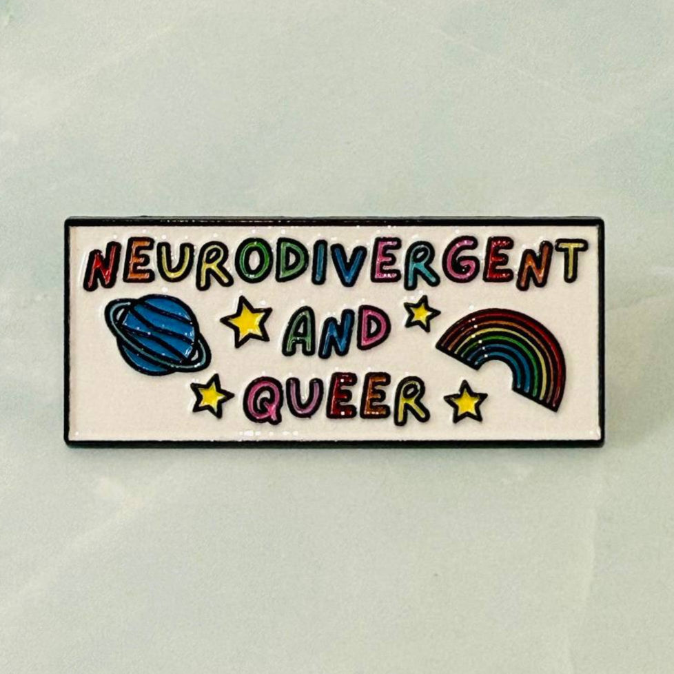 Enamel pin with 'Neurodivergent and Queer' text and symbols on a light background