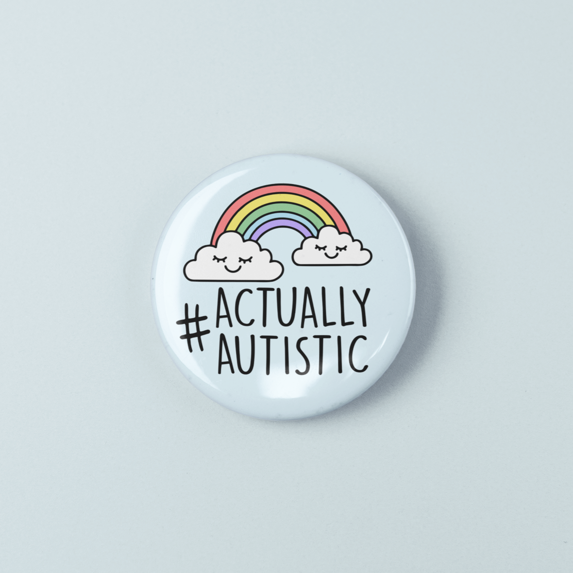 Button badge with '#Actually Autistic' text and rainbow design on a light gray background