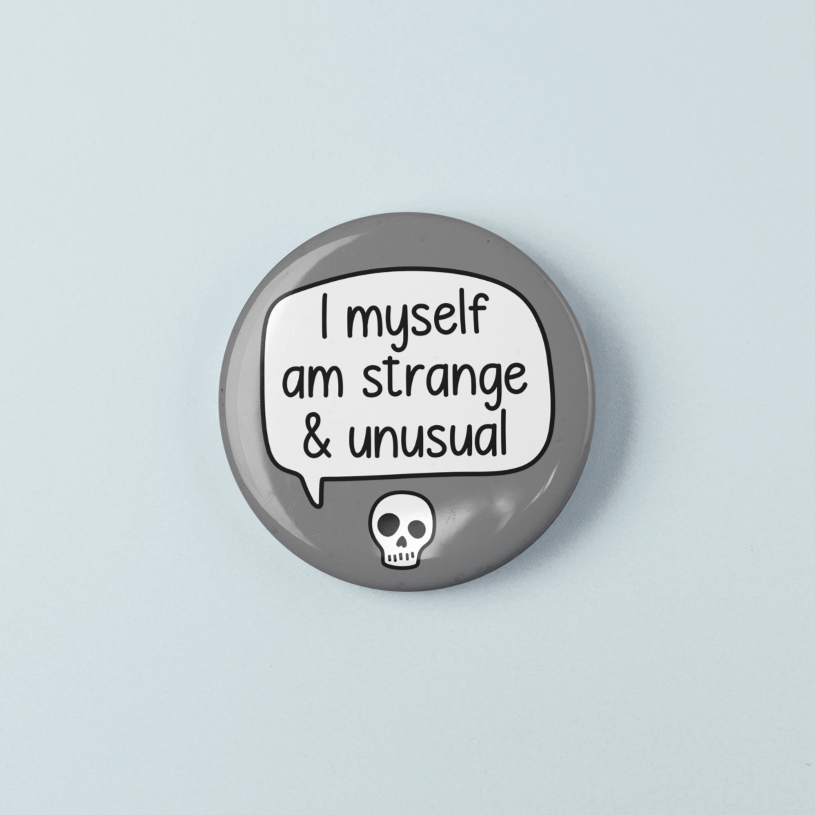 Button badge with text 'I myself am strange & unusual' and a skull design on a light blue background