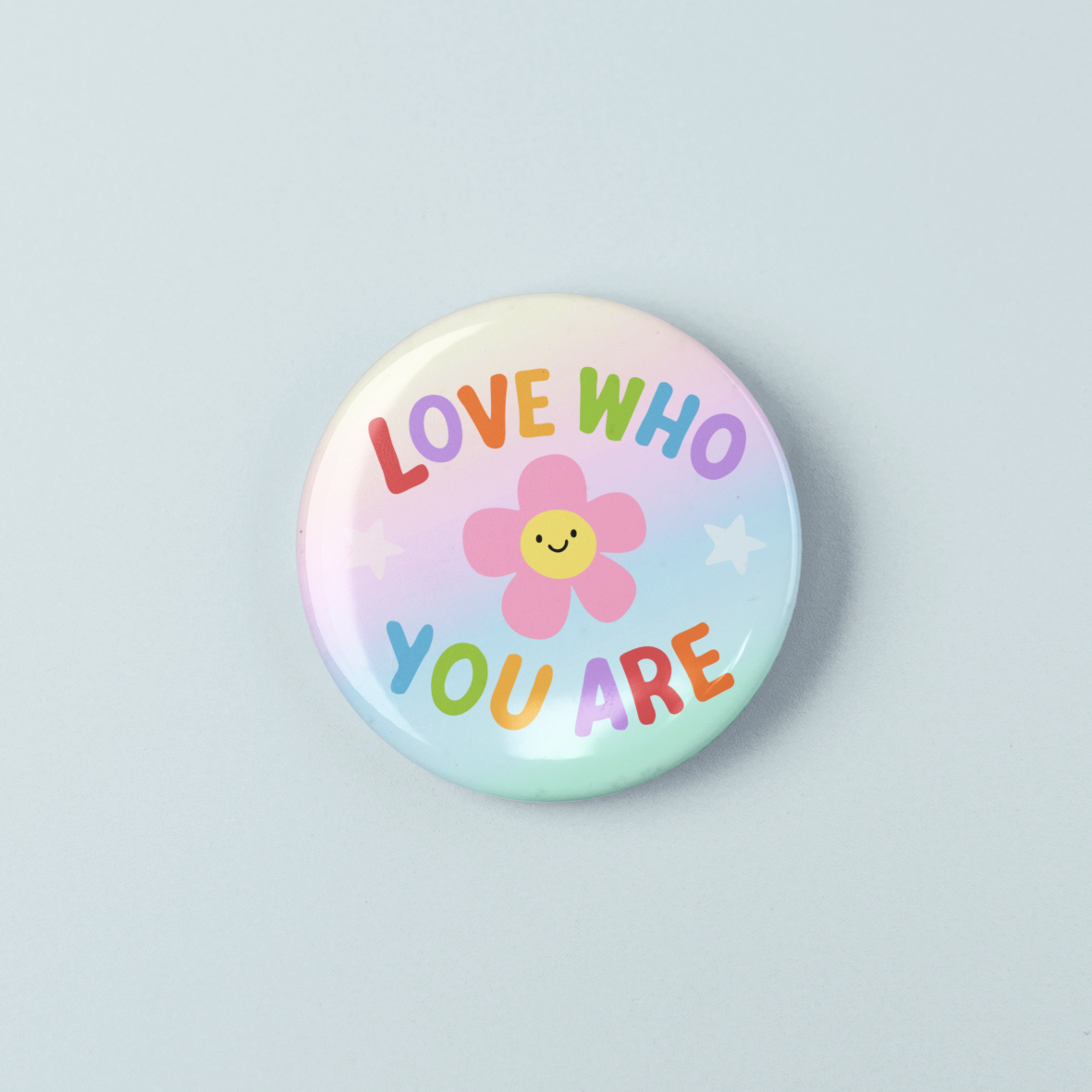 Button badge with 'Love who you are' text and a flower icon on a light blue background