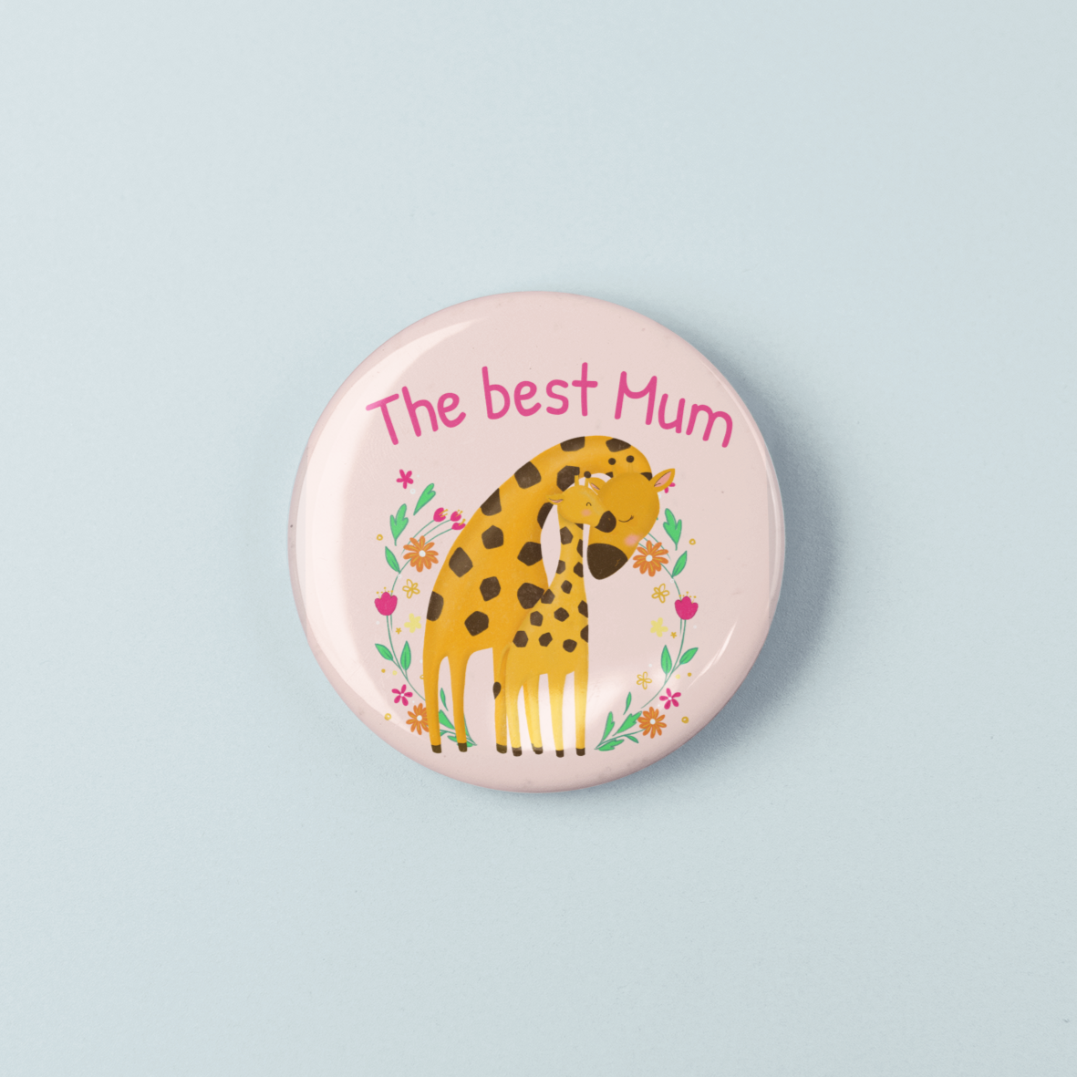 Button badge with a giraffe illustration and 'The best Mum' text on a light blue background