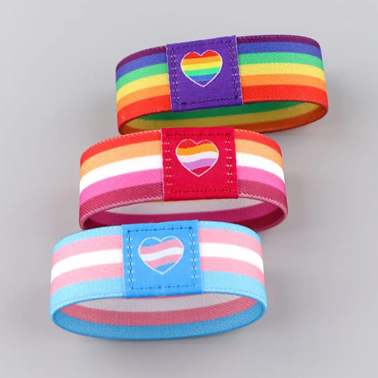 Three colorful striped dog collars with heart-shaped patches on a gray background